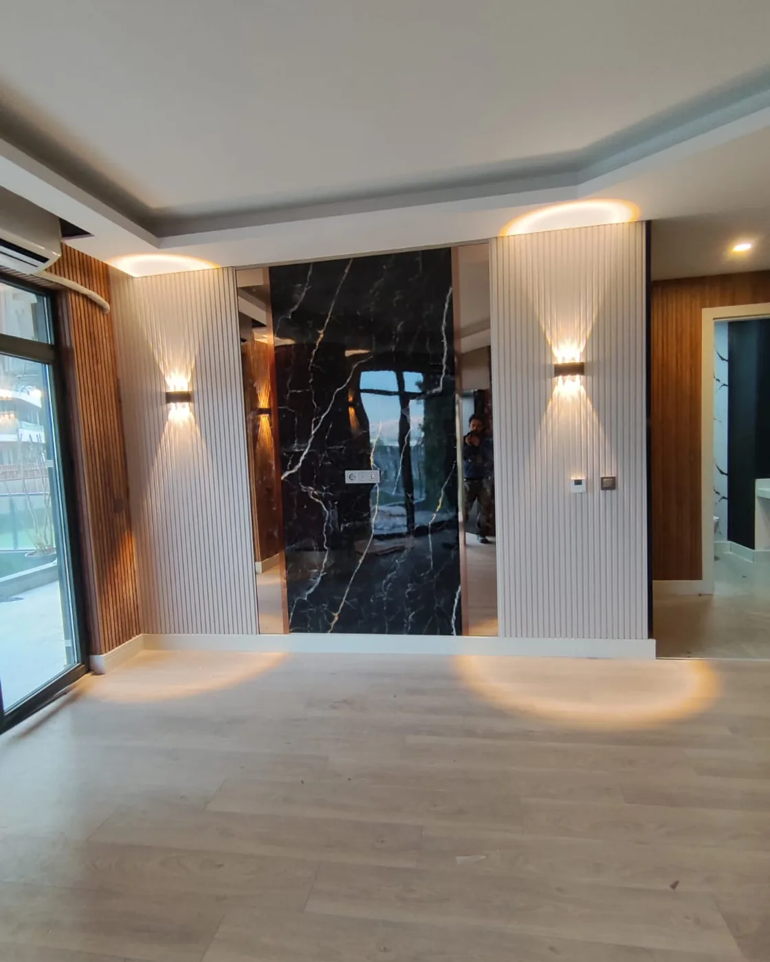 Yenilenen salon — siyah mermer panel, ahşap çıta kaplama ve aplik aydınlatma